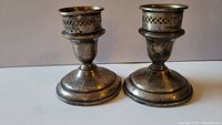 Pair of vintage sterling silver candle holders with wide bases and perforated decorative rims.