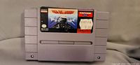 Front view of the SNES UN Squadron cartridge showing the label with artwork and price sticker.