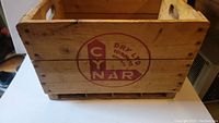 Side view of the wooden crate showing the red Cynar Dry logo stamped on the side with cut-out handles.