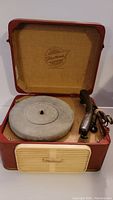 Vintage Fleetwood portable record player in reddish-brown case with beige fabric interior and Fleetwood logo inside lid