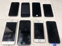 Eight devices laid out on cloth background: seven iPhones and one iPod Touch