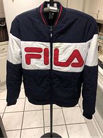 Full front view of navy blue FILA jacket with white horizontal stripe and red logo across the chest.