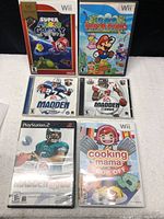 Photo of all 6 games showing covers Super Mario Galaxy, Super Paper Mario, Cooking Mama Cook Off, and 3 Madden football games.