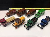 Front angled view showing all eight Lledo beer themed diecast trucks with measuring tape background measuring about 15 inches long.