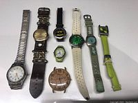 Full lot of 8 wristwatches laid side by side showing different styles and straps