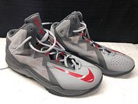 Right and left sides of the grey and red Nike Max Air basketball shoes, showing overall design and color.