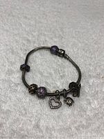 Full view of Pandora charm bracelet with multiple charms laid flat on white textured surface.