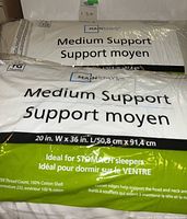Two king size medium support pillows in sealed packaging with brand Mainstays and product details visible.