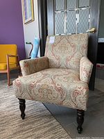 Armchair angled view showing upholstery paisley pattern and dark wooden legs