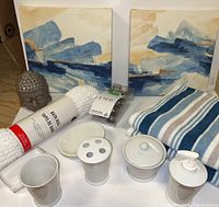 Overview of bathroom decor items showing two canvas paintings, bath towels, bath rug, vanity accessory set, and Buddha head statue