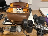 Full view of Fujica AZ-1 camera with leather case open showing camera body, lens in leather case, multiple straps, and accessories spread on a flat surface.