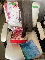 Lot items placed on a white chair, showing floral scarf, solid color scarf, umbrella and box