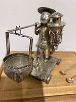 Close-up of silver-plated figural peddler condiment server showing basket and pepper shaker