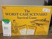 Yellow game box labeled The Worst-Case Scenario Survival Game with illustrations of a swimmer and a shark, showing it's the English edition and new in box.