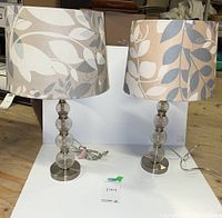 Two table lamps with leaf patterned fabric shades and stacked glass/acrylic bases placed on white background.