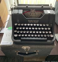 Frontal view of Underwood typewriter on top of storage case showing keyboard layout and body.