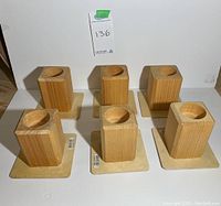 Front view of six wooden bed lifts arranged in two rows, showing square blocks with circular recesses on wooden square bases.
