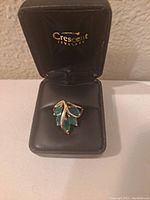Front view of gold ring with emerald cluster in display box