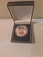 Front of the 1999 American Eagle silver dollar coin featuring colored Lady Liberty design in protective capsule and display box.