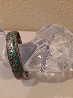 Silver cuff bracelet with turquoise inlay on a clear display stand