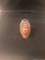 Front view of vintage large sterling silver ring with central oval coral stone and surrounding detailed silver engraving.