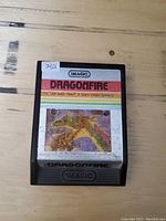Dragonfire game cartridge with label and cartridge body shown on wooden surface.