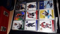 First photo showing nine hockey cards in a binder sleeve with players from various NHL teams.