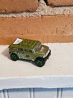 Side and angled views of green Hot Wheels Hulk-themed diecast toy car showing side decals and wheels.