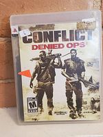 Game case front cover showing soldiers and game title Conflict Denied Ops, PlayStation 3 branding visible.