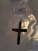 Stamped 925 silver cross pendant lying flat inside plastic packaging with a small paper tag labeled 185