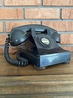 Side angle of black antique rotary dial Northern Electric phone showing handset resting on base.