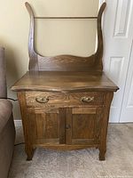 Front view of the antique oak washstand showing drawer, double doors, and towel bar.