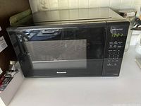 Black Panasonic microwave oven on countertop, front view