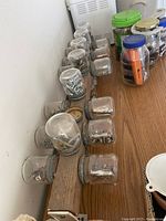 Photo showing glass jars filled with nuts, bolts, screws on a wooden rack on a wooden surface.