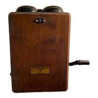 Front view of the wooden hand crank telephone with visible brass nameplate.