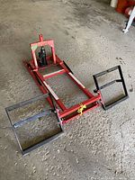 Full view of the red metal lawn mower lift frame with black adjustable brackets for holding the mower.