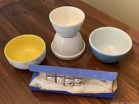 Top view of two ceramic bowls and a box with four silver-tone napkin rings