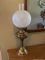 Front view of vintage hurricane oil lamp with frosted etched glass shade and brass base.