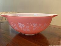 Side view of the vintage pink Gooseberry Pyrex mixing bowl showing the white gooseberry and leaves pattern on pink background.