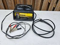 Wide shot of battery charger with attached cables and power cord.