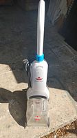 Full view of Bissell ReadyClean carpet cleaner standing upright on a concrete floor showing the entire unit and power cord.