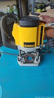 Front view of the DeWalt plunge cut router showing the yellow body, handle, power cord, and base plate.