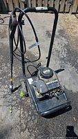 Full view of gas powered pressure washer showing frame, handle, hoses, and engine.