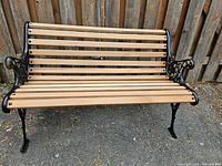 Front view showing bench with cedar seat and back slats between cast iron supports