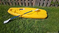 Kayak laid flat on grass, paddle assembled across top