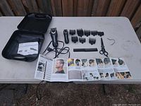 Wide view of Wahl hair cutting kit items laid out on table including clippers, trimmer, guards, comb, scissors, case and instruction manual.