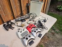 Xbox 360 console, controllers, Kinect sensor, wired headset, microphones and accessories laid out on a table
