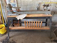 Overview of lathe on stand with wooden tool rest rack, manual and power cord visible