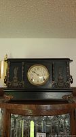 Full front view of the vintage black wood mantle clock showing the clock face with Arabic numerals and copper-toned metal decorative accents.