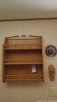 Full view of 3-tier wood wall shelf mounted on wall with decorative wooden hat and cutting block nearby